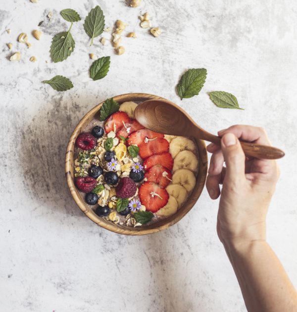 přírodní miska z teakového dřeva na smoothie bowl velká se smoothie a lžící v ruce