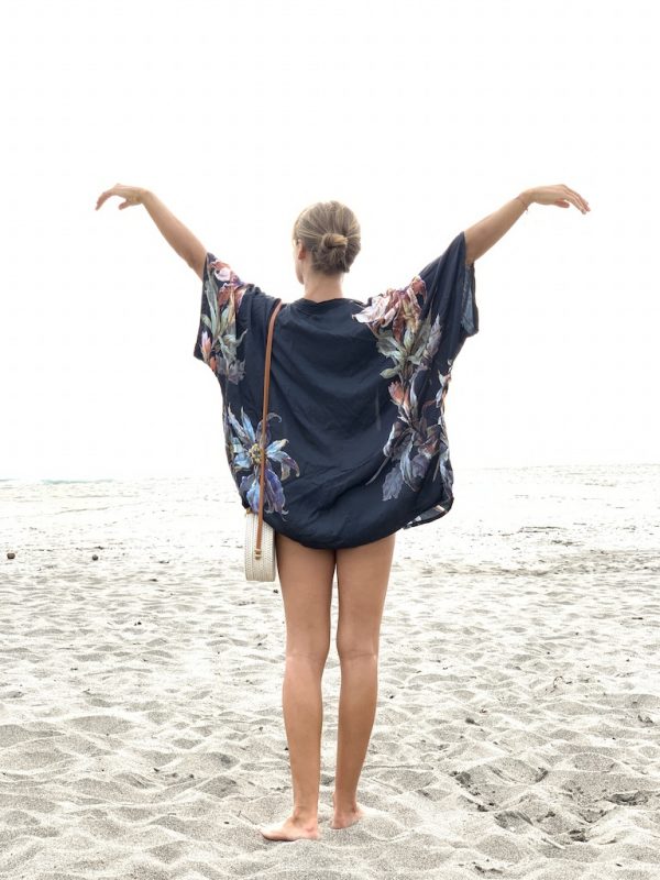 Kimono Bouquet v černé barvě s velkými modrými a zlatavými květy na pláži